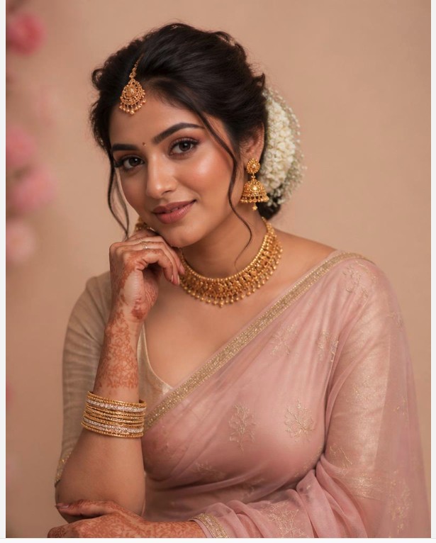 Woman in a pink saree with traditional gold jewelry